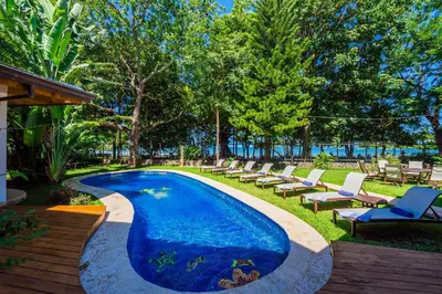 a swimming pool with chaise lounge chairs next to a resort at Blue Jewel Oceanfront Private Villa in Tamarindo
