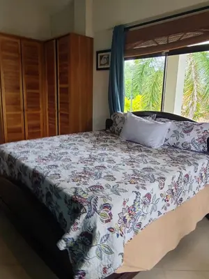 a bedroom with a bed with a floral bedspread and a window at Hermosa Beach House in Playa Hermosa