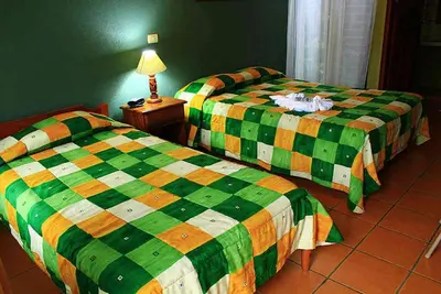 two beds sitting next to each other in a room at Hotel Guadalupe in Tilarán
