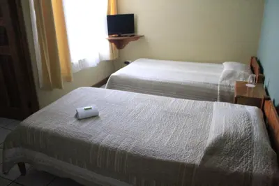 two beds in a hotel room with a box on the bed at Hotel Guadalupe in Tilarán