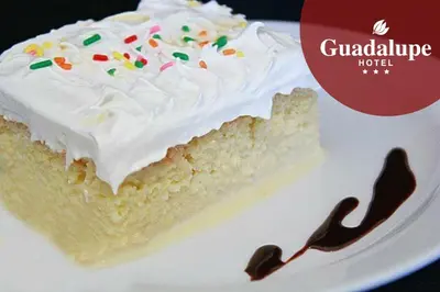 a piece of cake with white frosting and sprinkles on a plate at Hotel Guadalupe in Tilarán