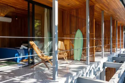 a row of chairs and a surfboard on a building at Somos in Santa Teresa Beach