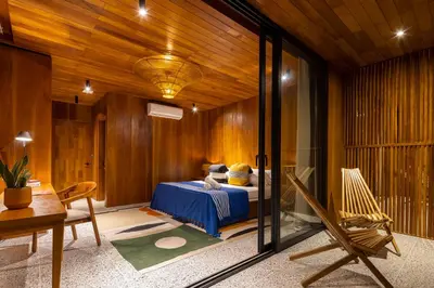 a bedroom with a bed in a room with wooden walls at Somos in Santa Teresa Beach