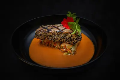 a black bowl with a piece of cake with a red flower on top at Noah's Forest by Tifakara in Fortuna