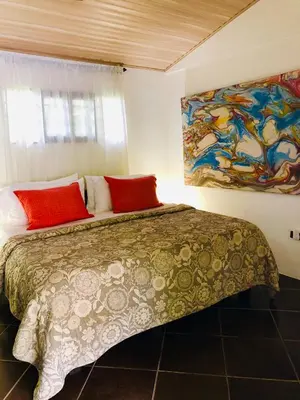 a bedroom with a bed and a painting on the wall at Cabinas D’Val in Uvita