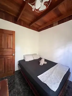 a small bedroom with a bed with a ceiling at Woodstock Hostel in Sámara