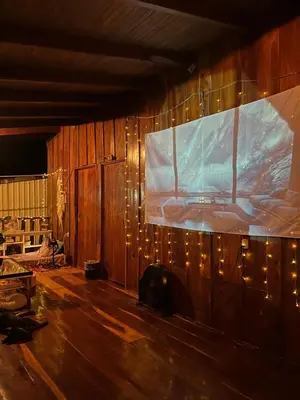 a living room with a large screen on the wall at Woodstock Hostel in Sámara