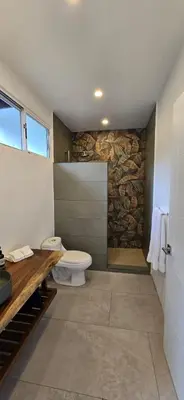 a bathroom with a toilet and a stone wall at Ojochal Gardens in Ojochal