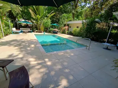 a swimming pool in a yard with an umbrella at Ojochal Gardens in Ojochal