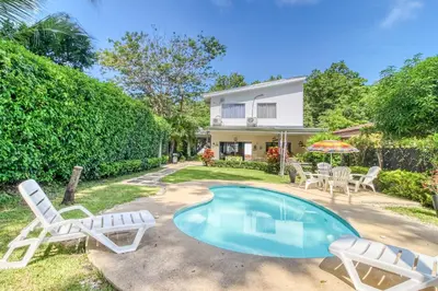 a villa with a pool and chairs and a house at Casa Sol in Carrillo