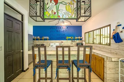 a kitchen with a bar with three stools at Casa Sol in Carrillo
