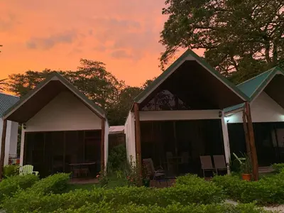 a house with two roofs with a sunset in the background at Villas Cabuya Beach & Jungle in Cabuya