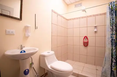 a bathroom with a sink and a toilet and a shower at Flor de Katty Hostel Airport in Alajuela City