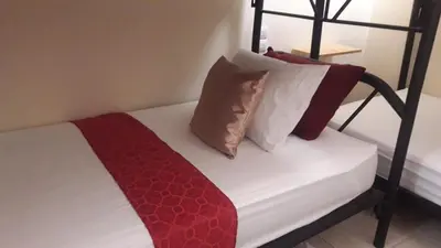a bed with red and white pillows on it at Flor de Katty Hostel Airport in Alajuela City