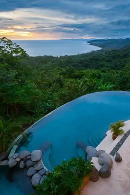 a swimming pool with a view of a forest at Villa Nimbu in Mal País