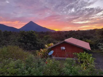 a red barn with a mountain in the background at Cabaña Rural el Mirador in Fortuna