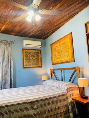 two beds in a bedroom with a ceiling fan at Hotel Boruca Tamarindo in Tamarindo