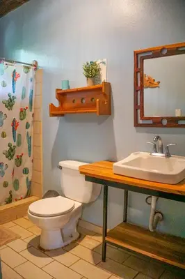 a bathroom with a toilet and a sink and a mirror at Hotel Boruca Tamarindo in Tamarindo