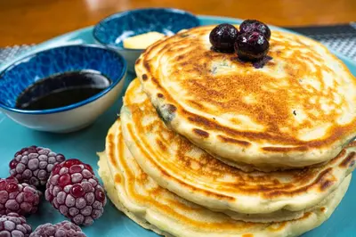a stack of pancakes on a blue plate with berries at Hotel Boruca Tamarindo in Tamarindo