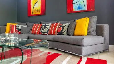 a living room with a gray couch with colorful pillows at 3rd-floor space with modern décor recently renovated viewing over pool in Coco in Coco