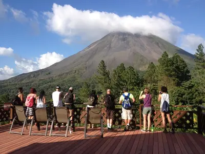a group of people standing on a deck looking at a mountain at Arenal Observatory Lodge & Trails in Fortuna