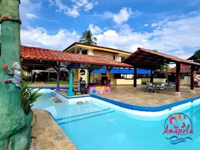 a resort with a swimming pool and a house at Amapola Resort in Jacó