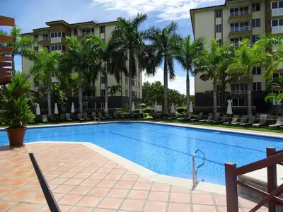 a swimming pool in front of a building with palm trees at 3Rooms Amaizing Beach Studio in Jacó