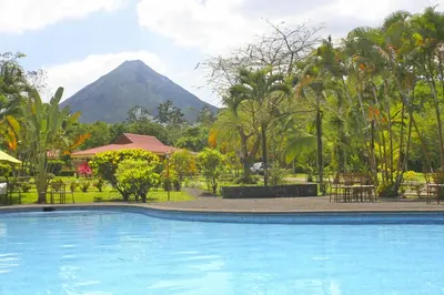 a swimming pool with a mountain in the background at Hotel Arenal Country Inn in Fortuna