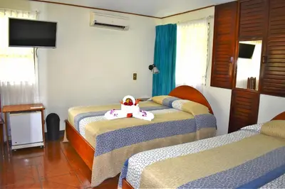 a bedroom with three beds with a teddy bear on the bed at Hotel Arenal Country Inn in Fortuna