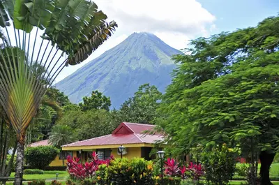 a mountain in the distance with a house and trees at Hotel Arenal Country Inn in Fortuna