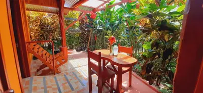a table and chairs on a porch with plants at Jardin entre Montañas in Bijagua