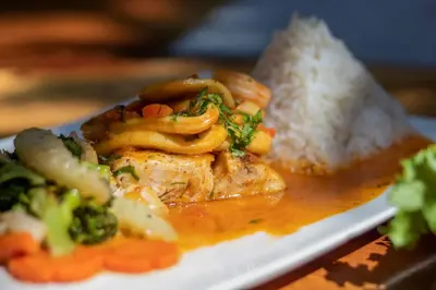 a plate of food with meat and broccoli and rice at Cafe Playa Negra Hotel in Playa Negra