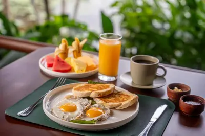 a table with two plates of eggs and toast and fruit at Maquenque Lodge in Boca Tapada