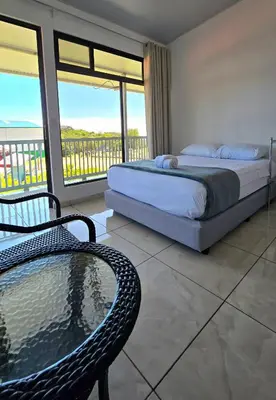 a bedroom with a bed and a chair and a balcony at Cattleya Family in Monteverde Costa Rica