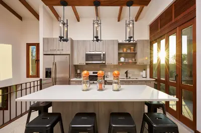 a kitchen with a large white island with black stools at Alouatta Guesthouse en Las Catalinas - Beachfront GUESTHOUSE for 6 people in Playa Danta