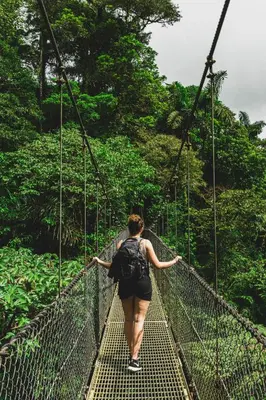 a woman walking across a suspension bridge in the jungle at Alouatta Guesthouse en Las Catalinas - Beachfront GUESTHOUSE for 6 people in Playa Danta