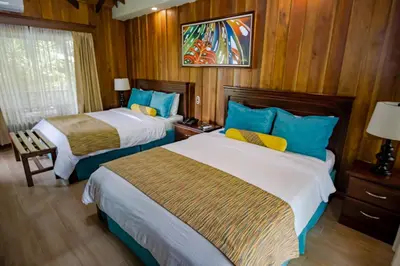 a hotel room with two beds with blue and yellow pillows at Hotel Lomas del Volcan in Fortuna