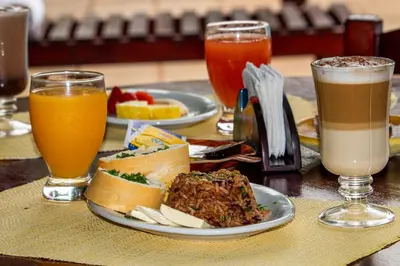 a table with two plates of food and two drinks at Hotel La Rosa de America in Alajuela City