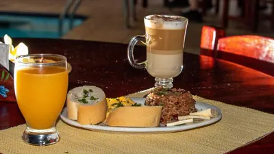 a plate of food and two drinks on a table at Hotel La Rosa de America in Alajuela City