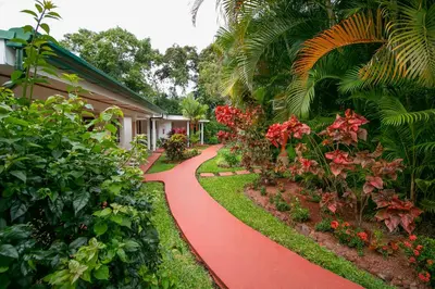 a red path in front of a house with flowers at Hotel La Rosa de America in Alajuela City