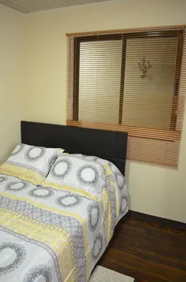 a bedroom with a bed and a window with a bedspread at #5 Private room close to Airport in Alajuela City