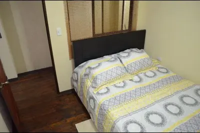 a bedroom with a bed with a comforter and a window at #5 Private room close to Airport in Alajuela City