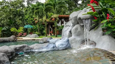 a waterfall in a swimming pool in a backyard at Hotel Mountain Paradise in Fortuna