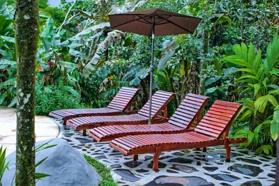 four chairs with an umbrella on a patio at Hotel Mountain Paradise in Fortuna