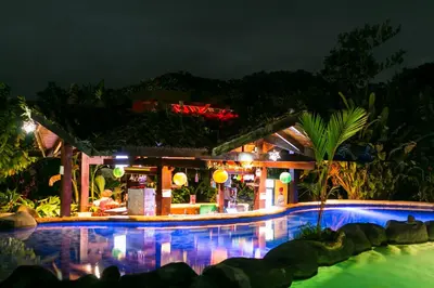 a resort with a pool and a bar at night at Hotel Mountain Paradise in Fortuna