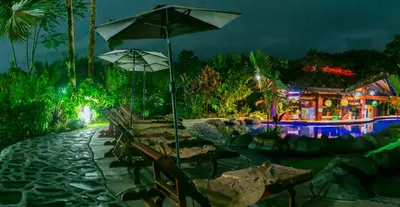 a group of chairs and an umbrella next to a pool at Hotel Mountain Paradise in Fortuna