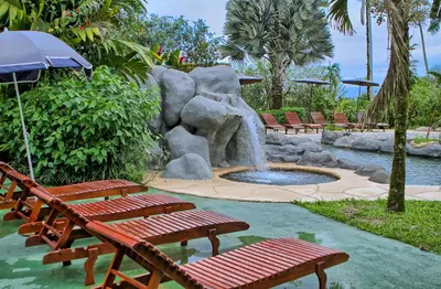 a fountain in a park with benches and a pond at Hotel Mountain Paradise in Fortuna