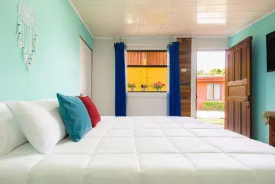 a bedroom with a large white bed with colorful pillows at Casa Mandala by Dreamcatcher in Sarchí