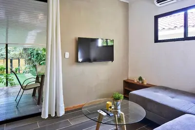 a living room with a couch and a tv on the wall at Villa Flamingo in Santa Teresa Beach