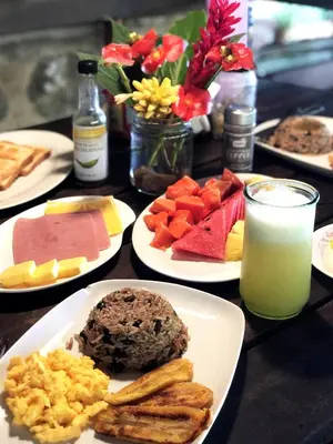 a table with plates of food and a glass of milk at Cascada Verde Eco Lodge & Hostel in Uvita